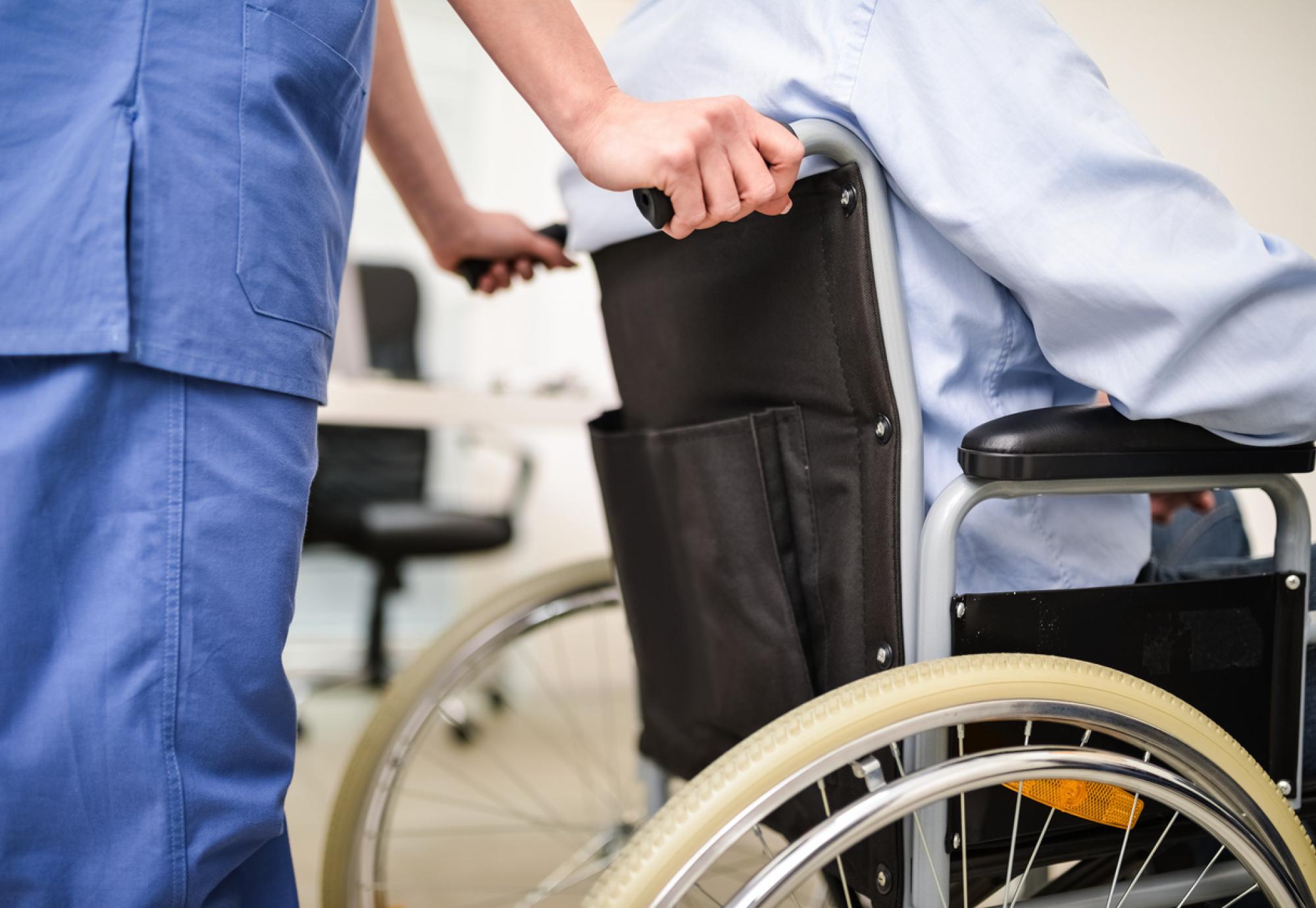 Nurse wheeling an elderly patient into hospital depicting a hospital admission
