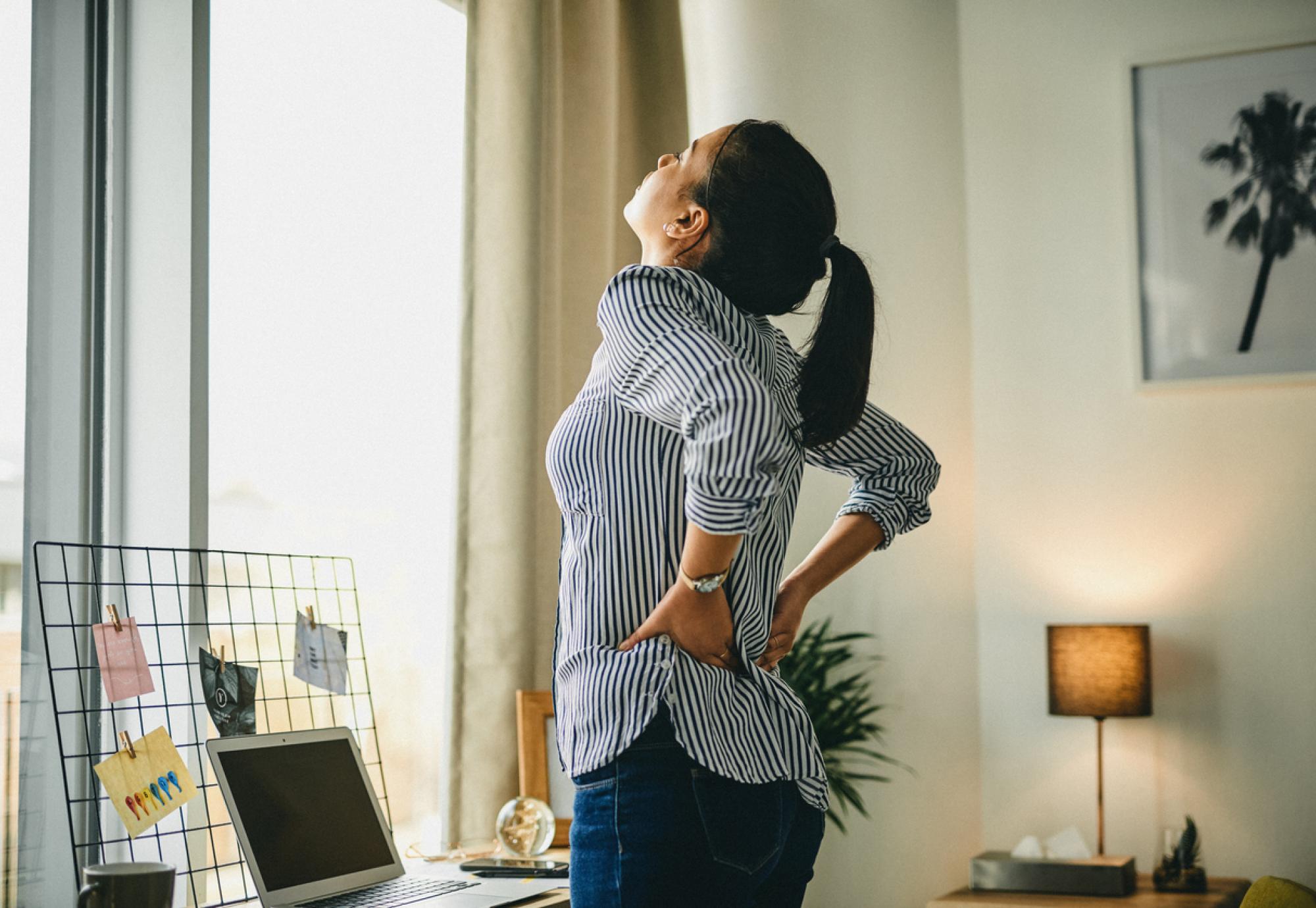 Image of a woman holding her lower back in pain depicting NICE's new recommendation of seven digital technologies