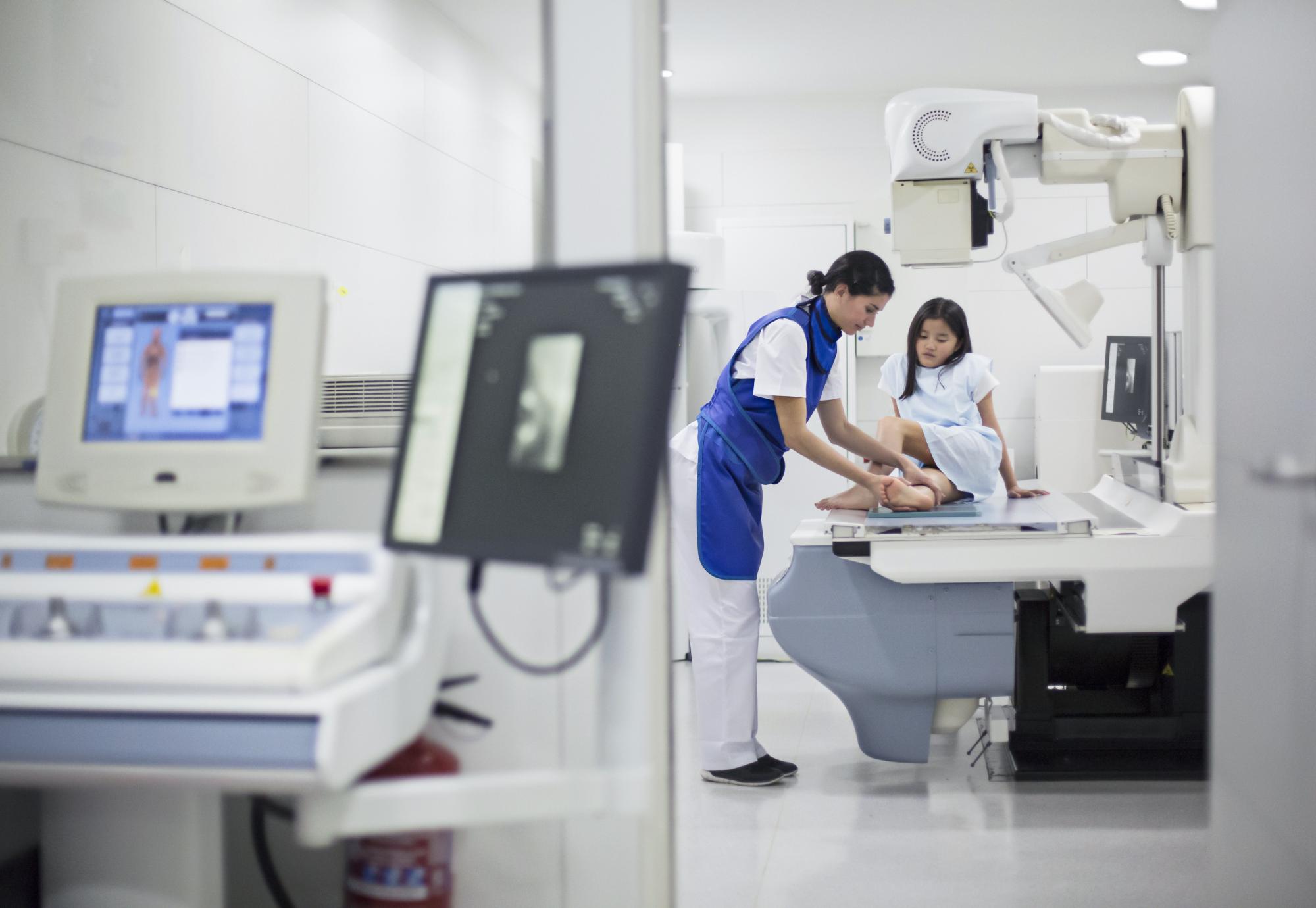 Girl having her leg scanned by an x-ray medical device