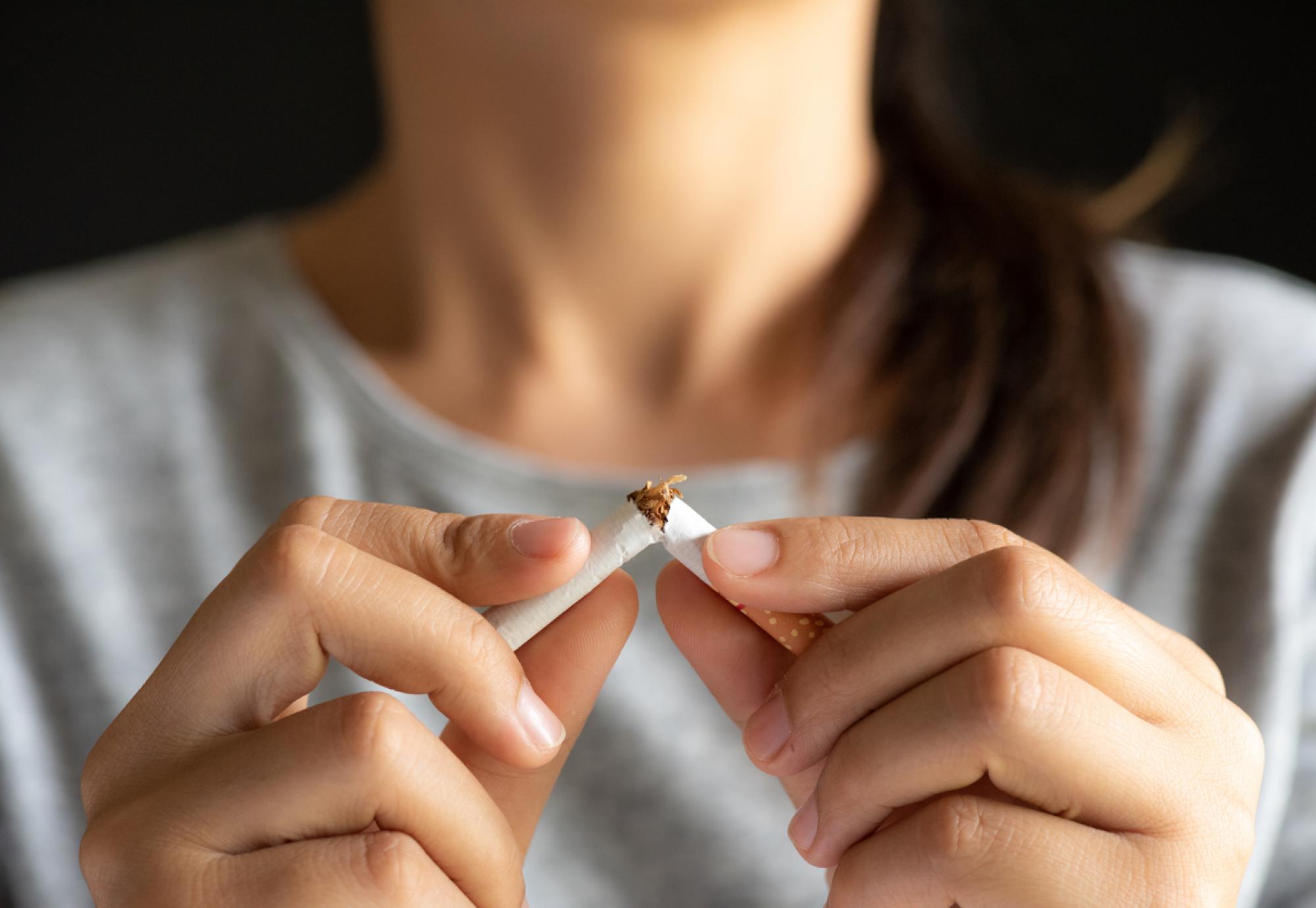 Woman breaking a cigarette in half depicting the government's stop smoking policy