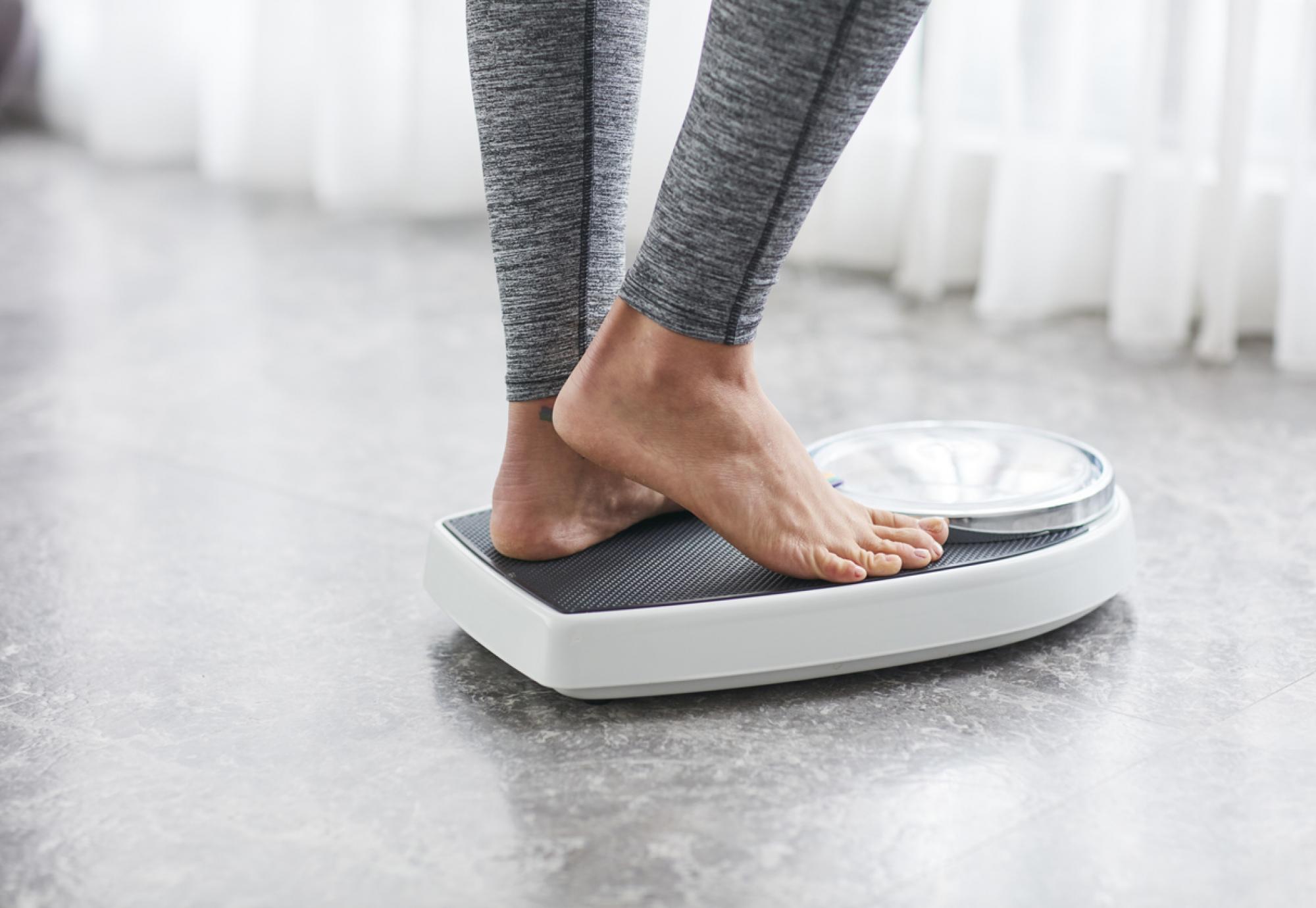 Woman standing on scales depicting weight loss