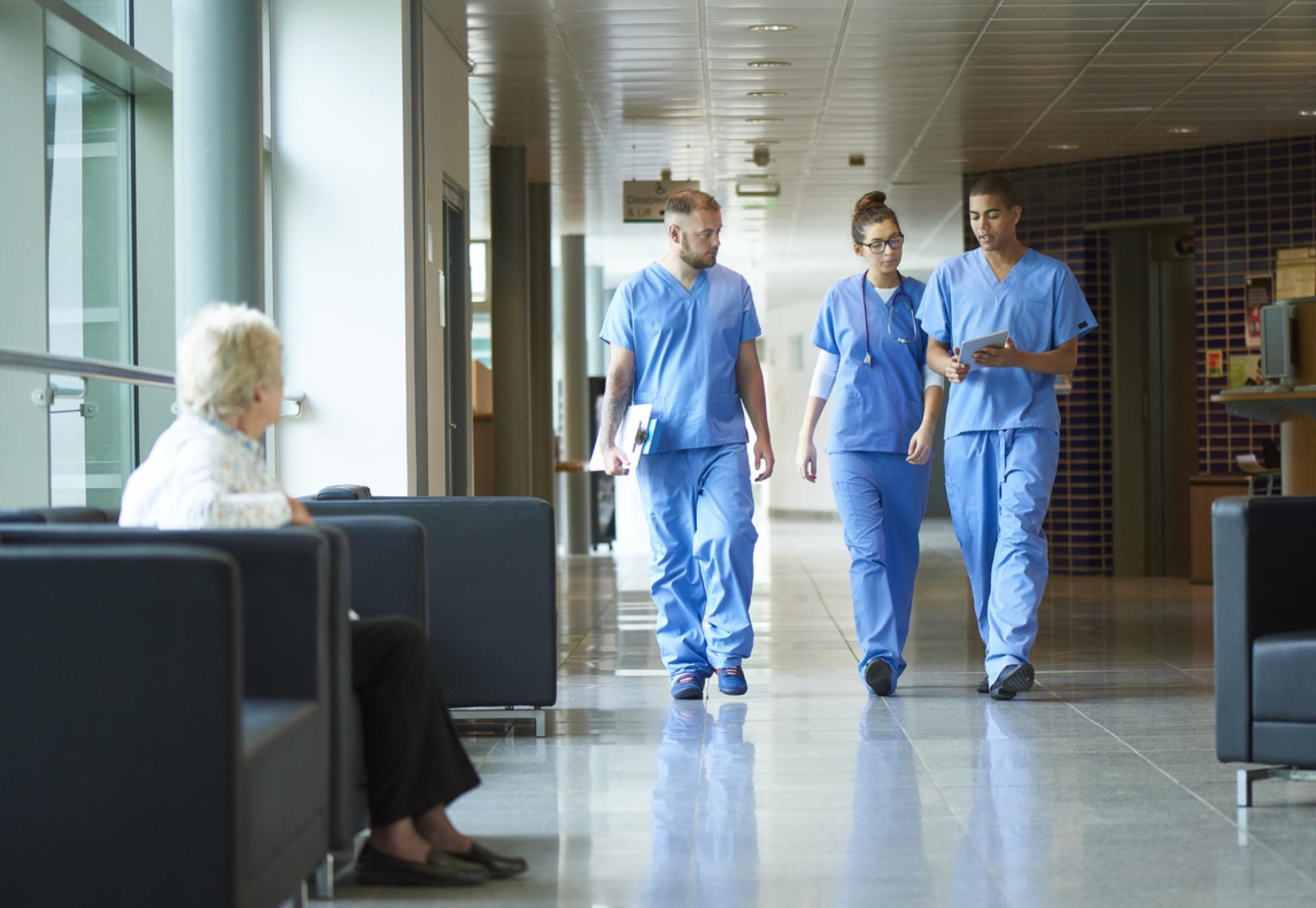 three junior doctors walking along a hospital corridor