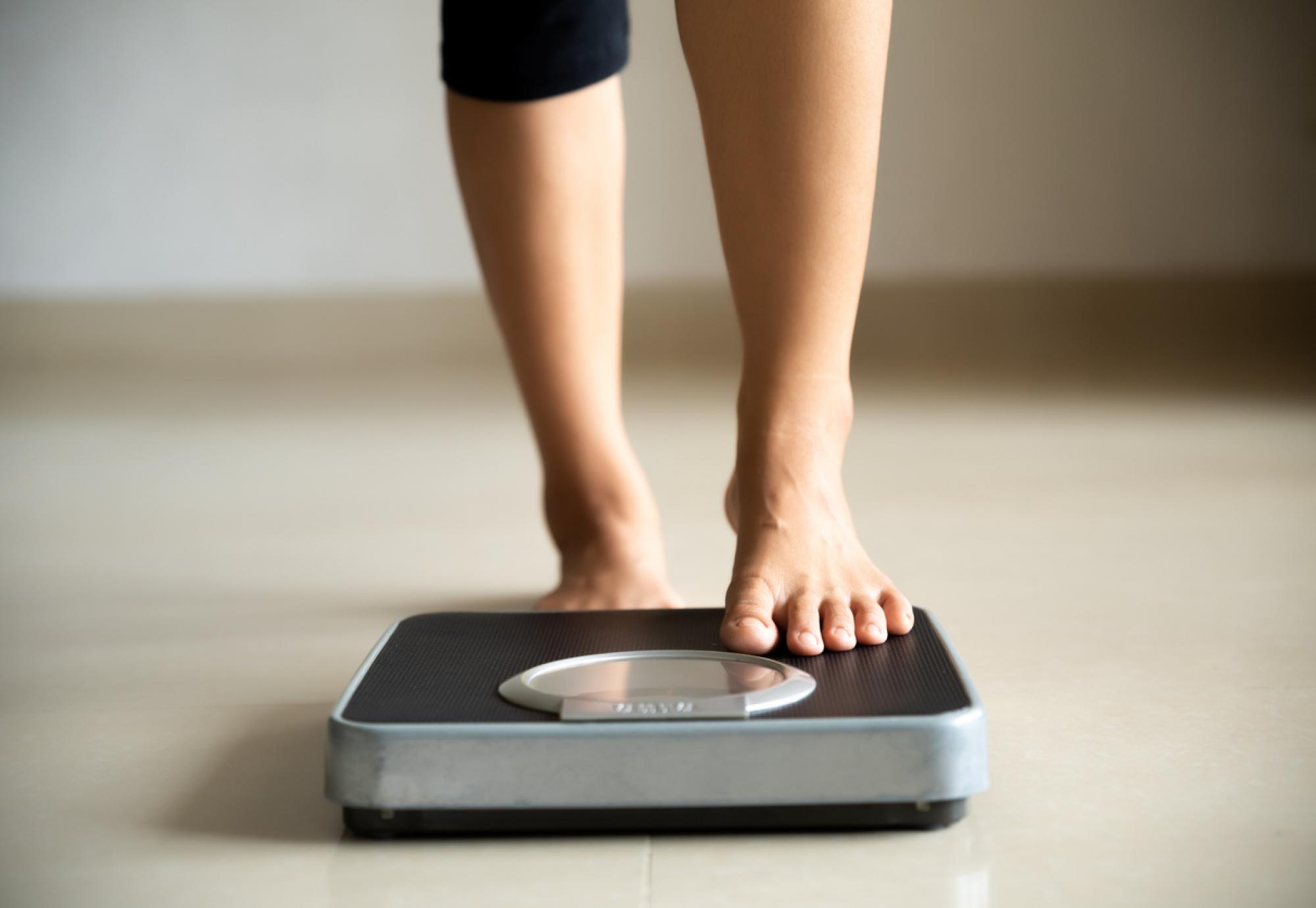 Female leg stepping on weigh scales