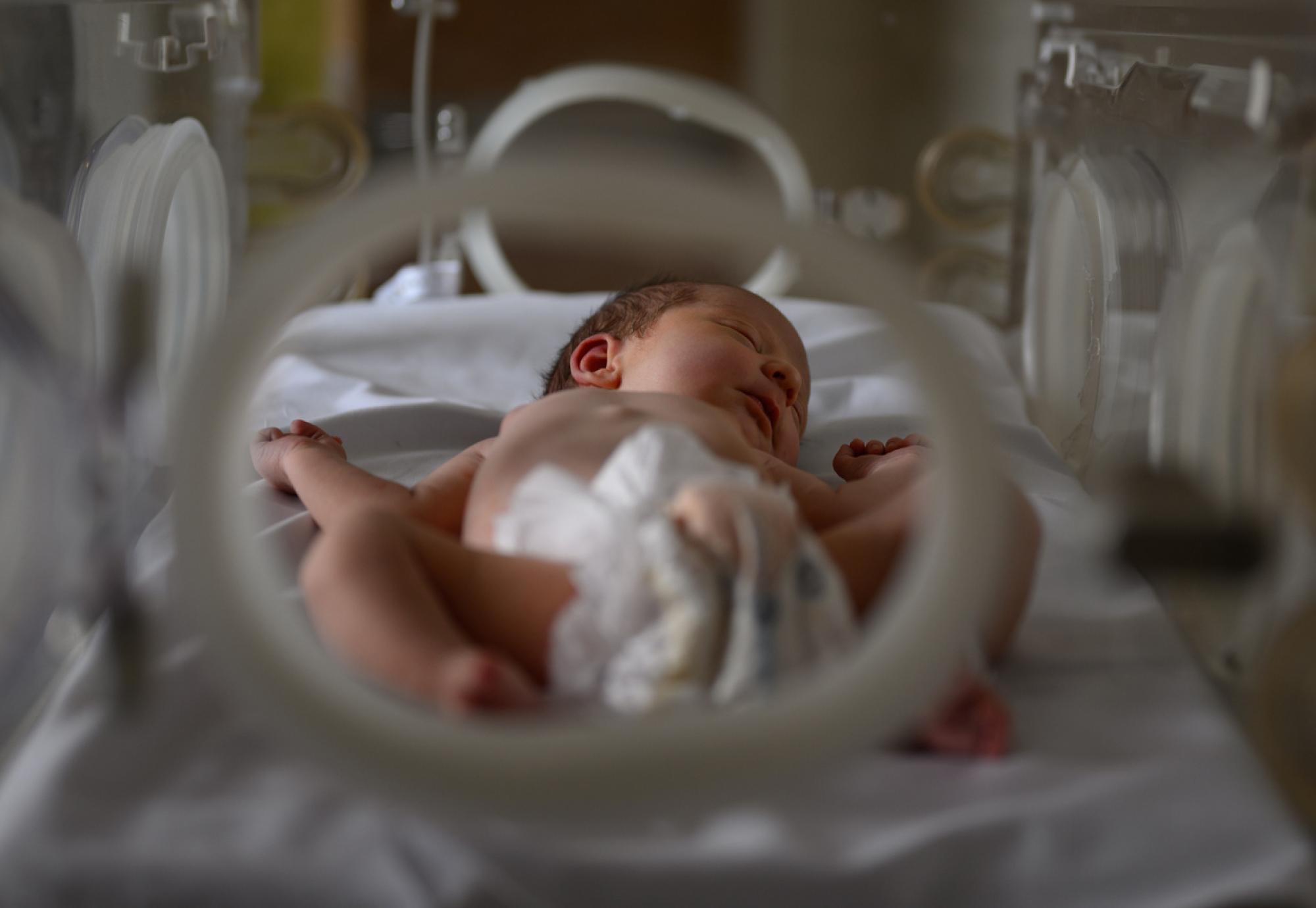 Newborn baby in hospital incubator