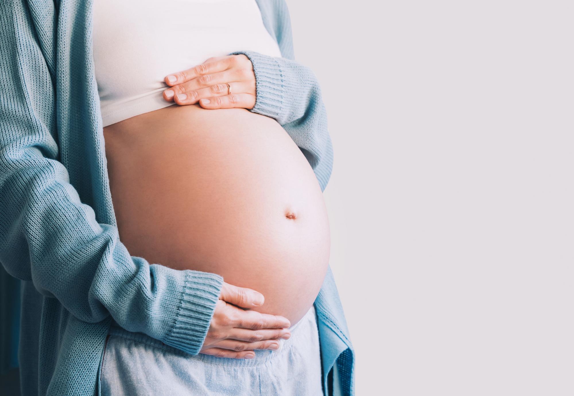 pregnant woman holds hands on her belly