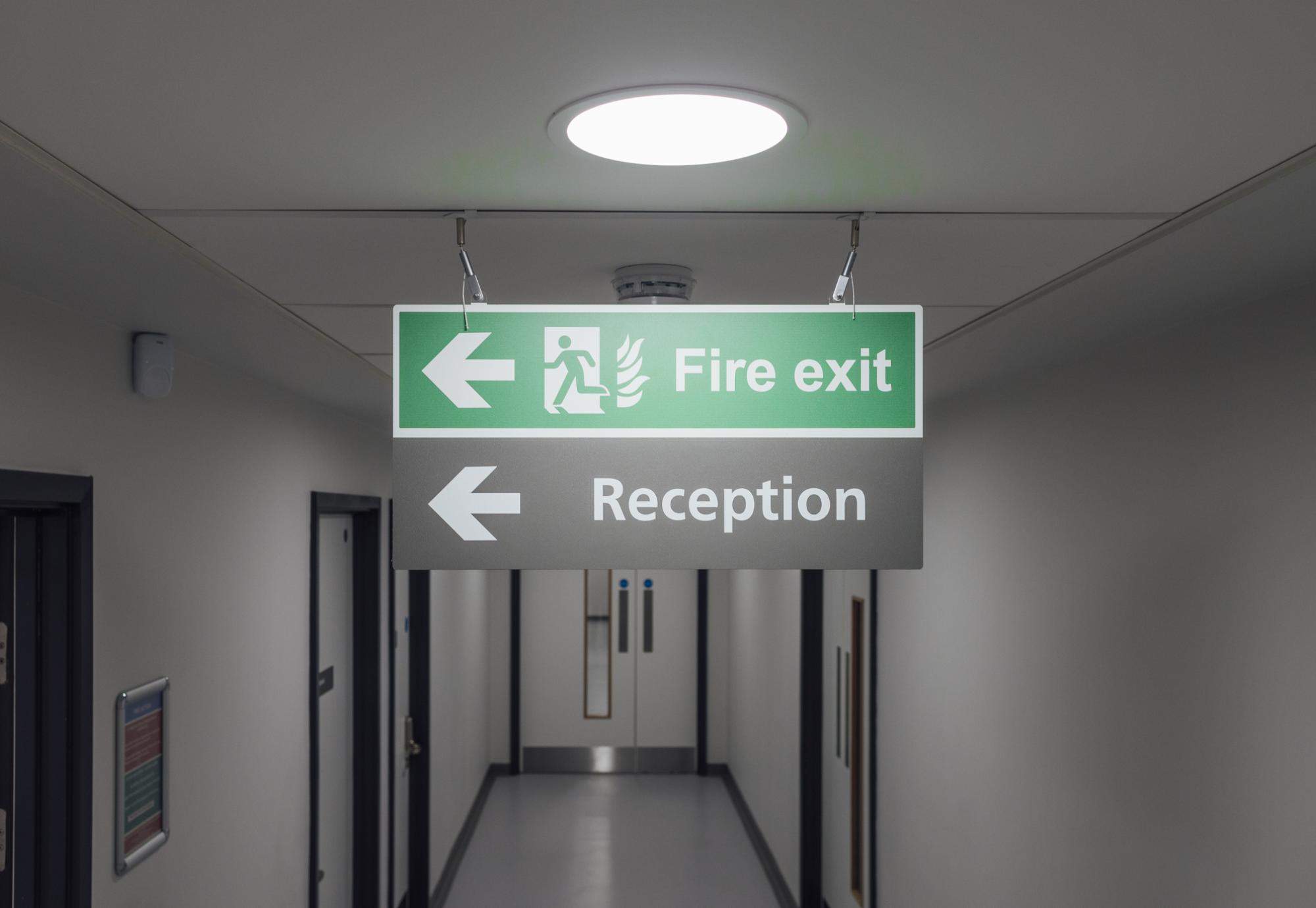 fire exit sign hanging from the ceiling in a hospital