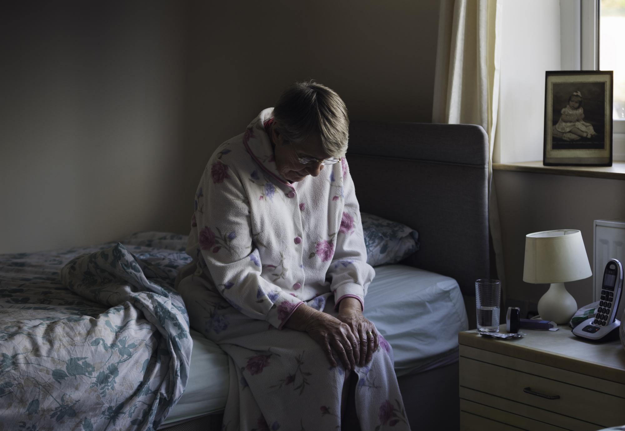 senior woman sitting on the side of her bed