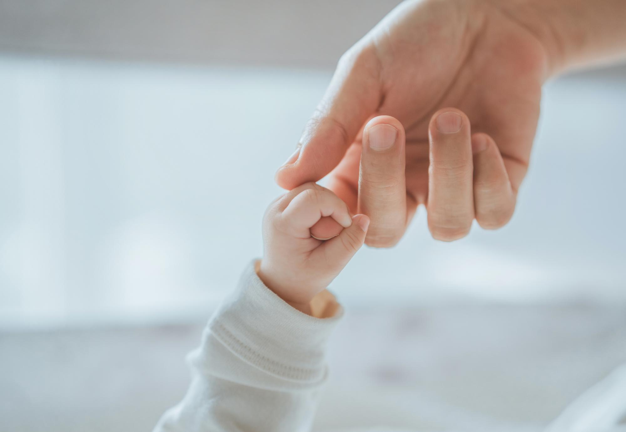 Newborn baby holding mothers finger