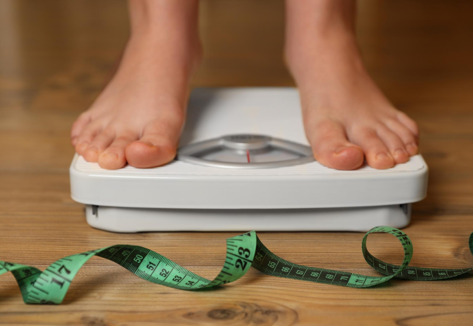 Overweight person using scales
