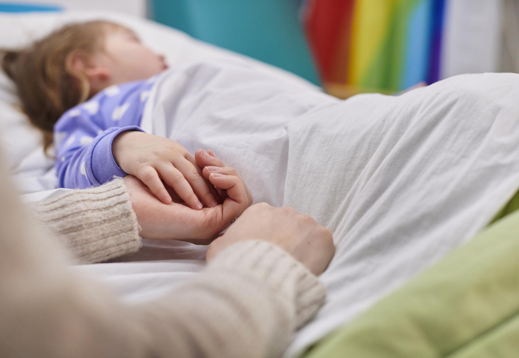 Mother and daughter holding hands in hospital