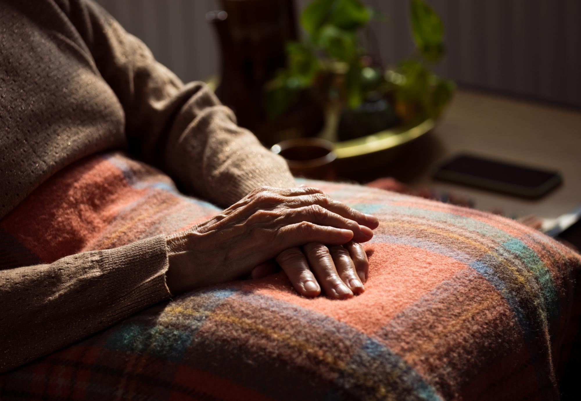 Senior woman sat under a blanket