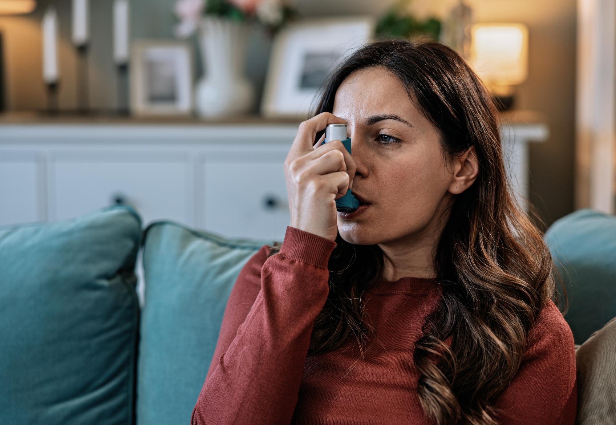 woman using her asthma inhaler at home