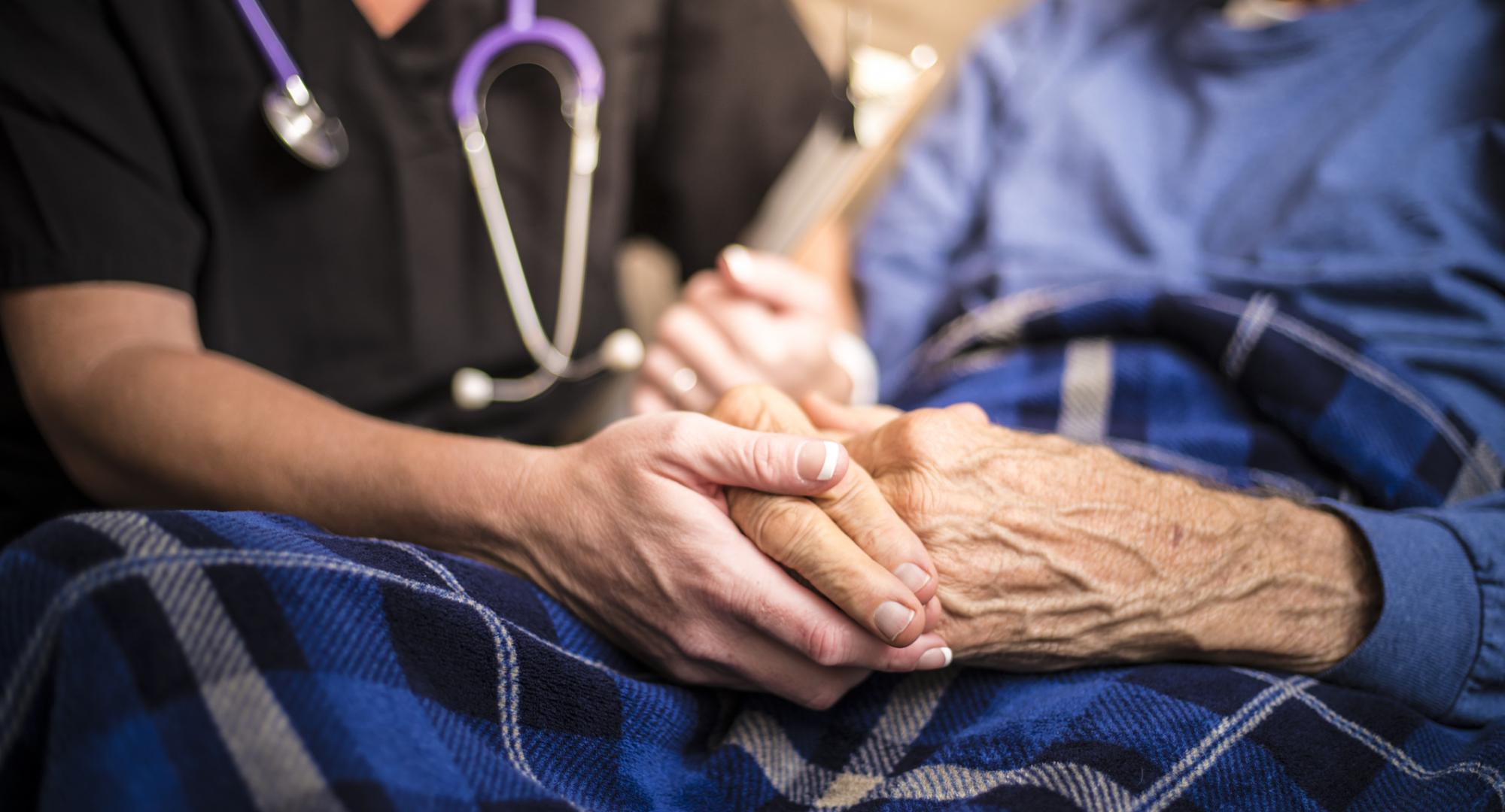 Nurse holding hand of elderly patient