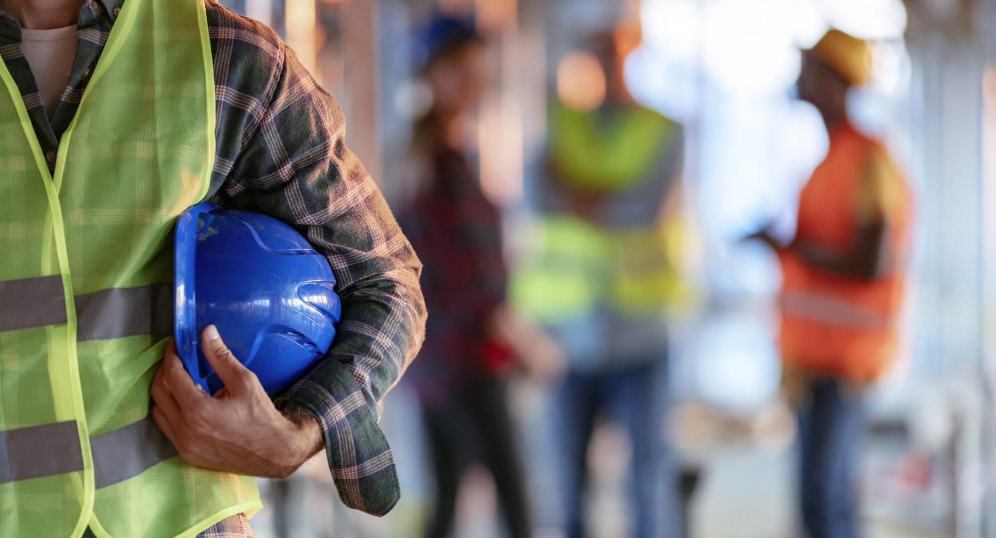 Workman holding hard hat tucked into elbow