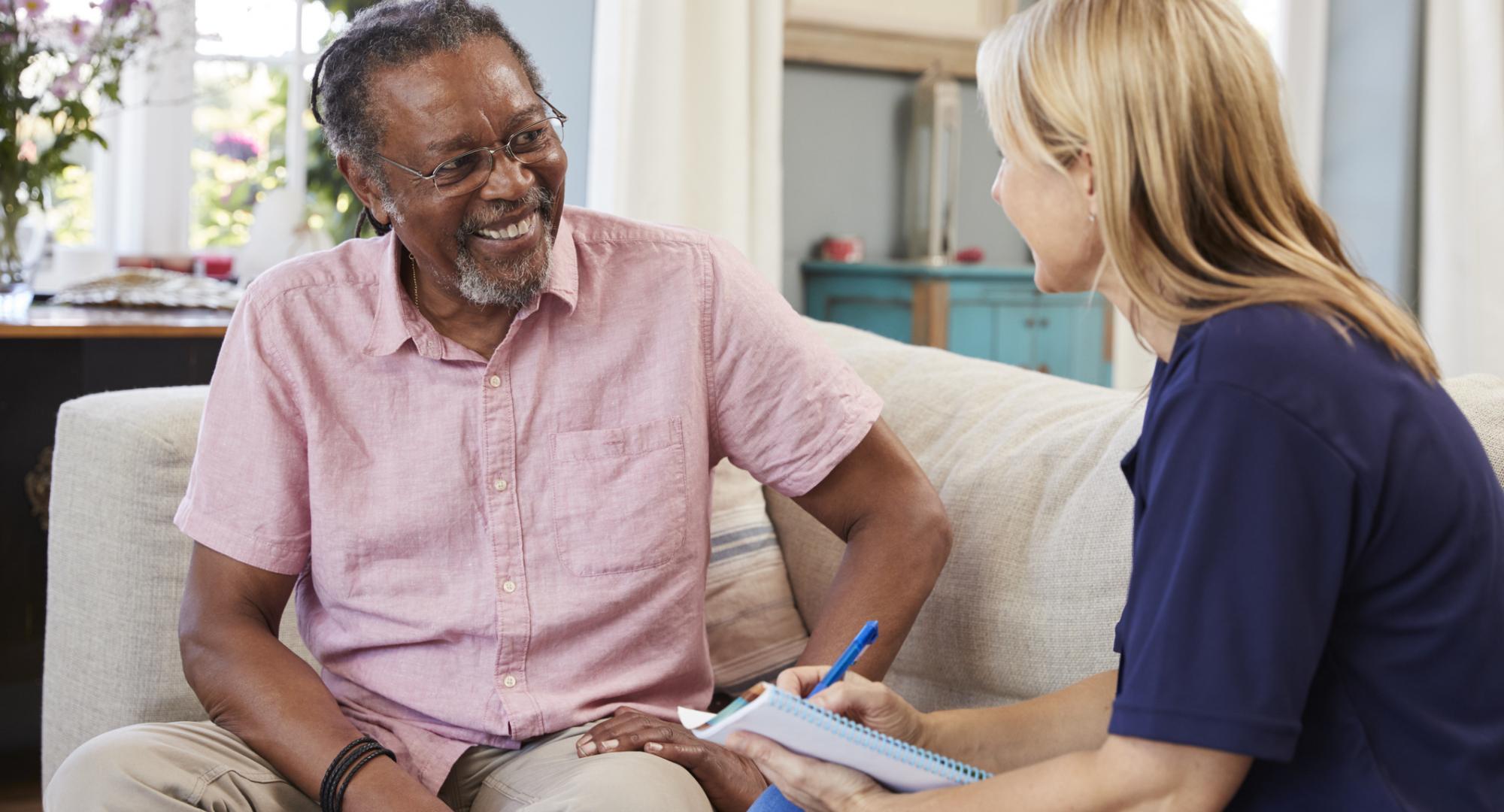 Female support worker talking with older male resident