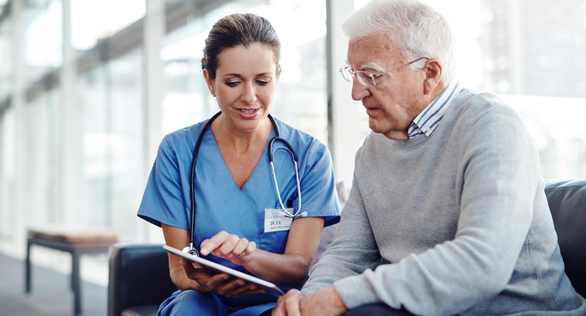 Female health professional with elderly patient using a tablet computer