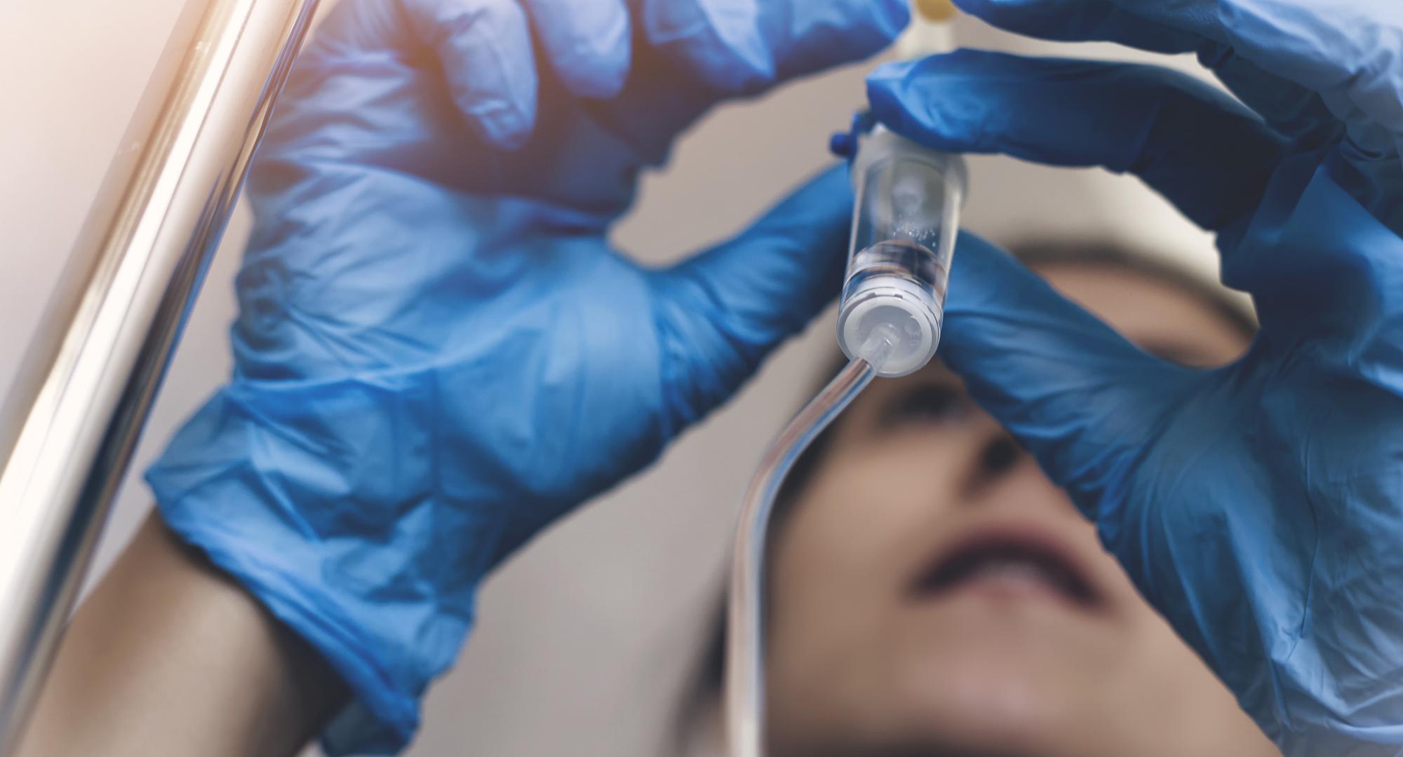 Woman attaches drip to vial. 