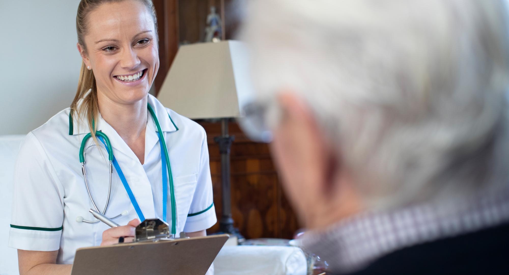 Female nurse recording information while interviewing a patient