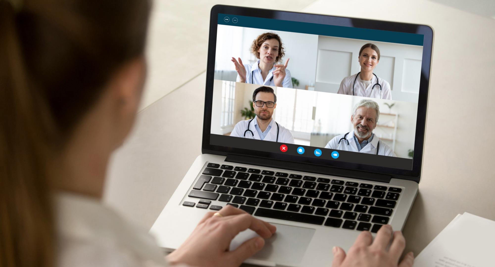 Doctor using a laptop to communicate virtually with colleagues