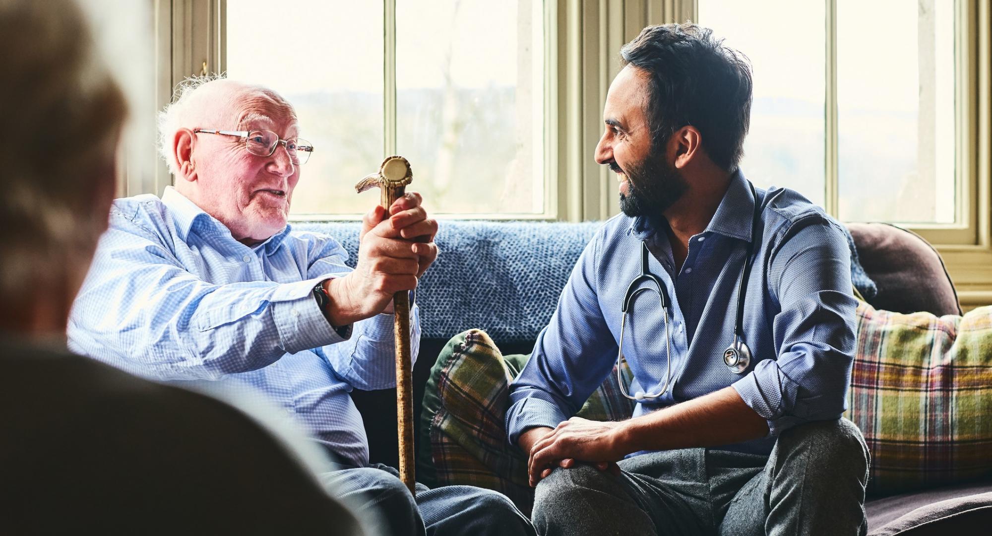 Elderly man with a cane talking with a male doctor