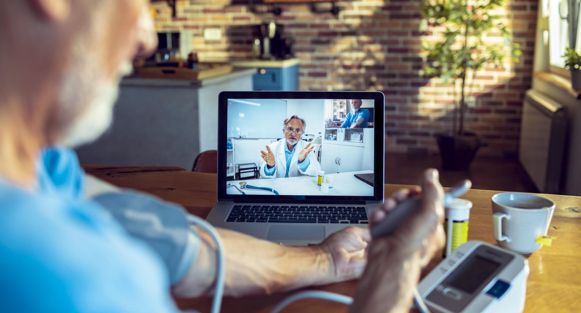 Doctor using remote video consultation with a patient taking their blood pressure