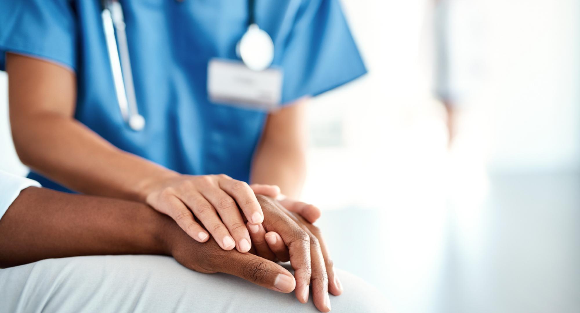 Nurses comforting patient with their hand