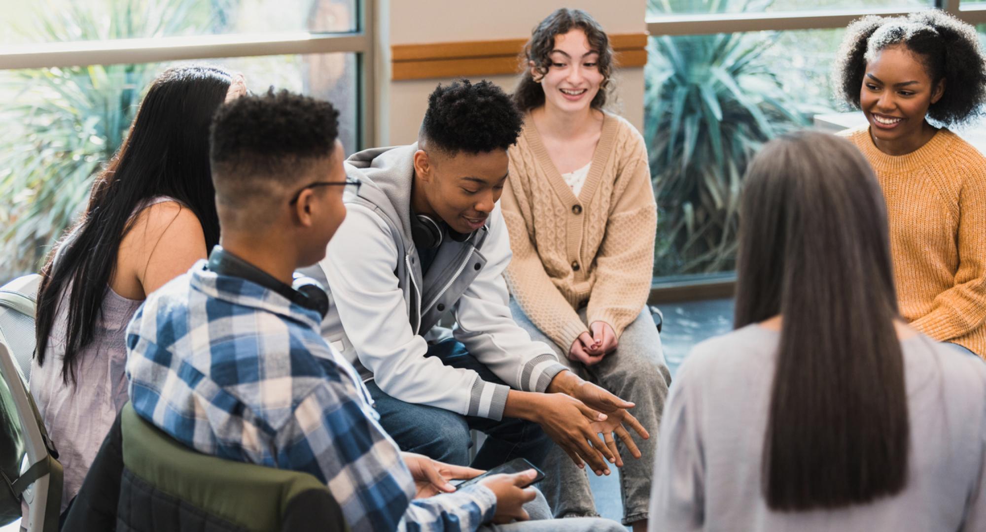 Group of young people sat in a circle talking