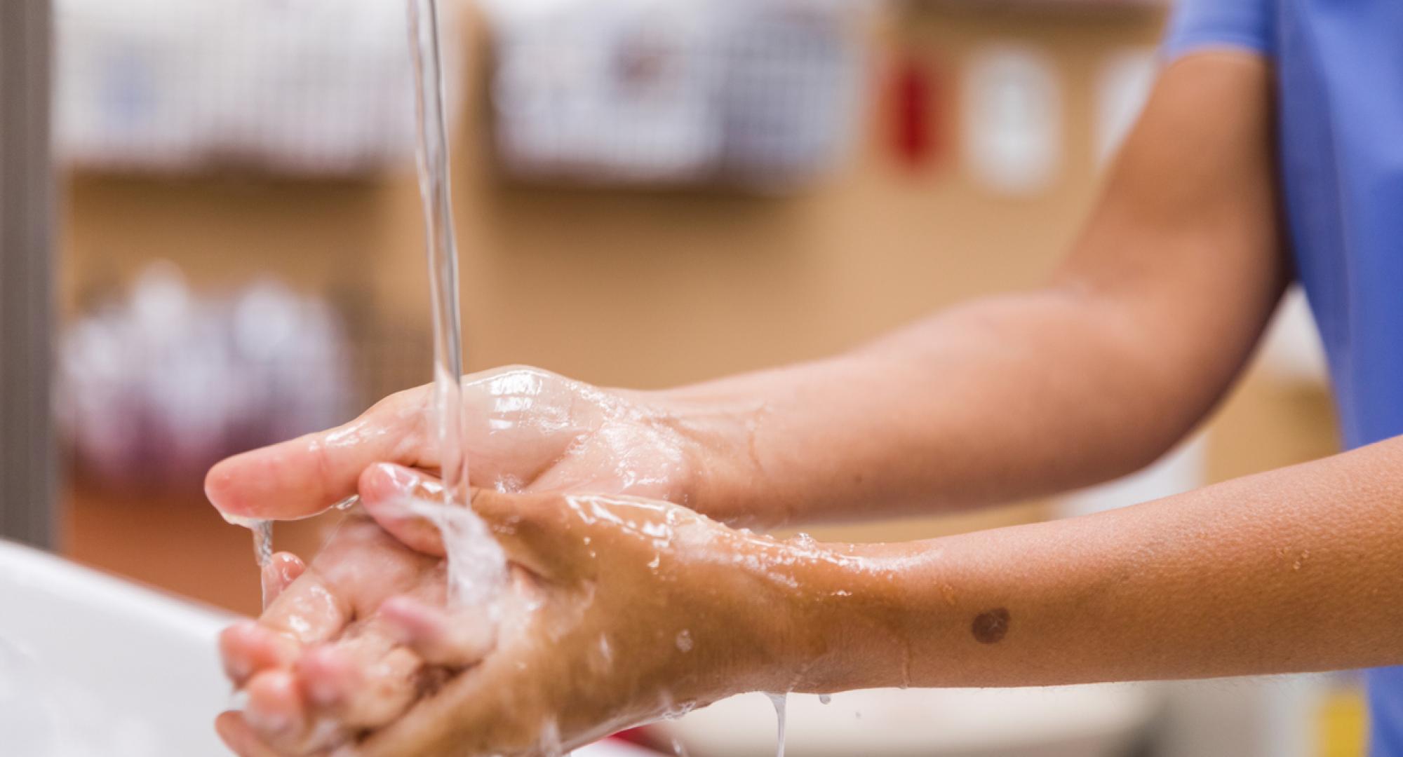 Healthcare worker washing their hands with water