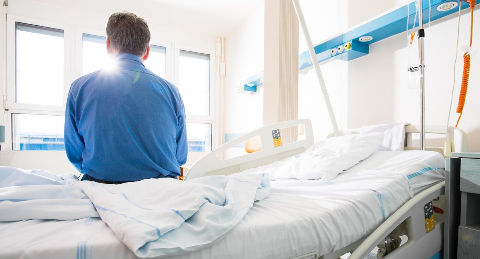 Man sitting on a hospital bed looking out of a window
