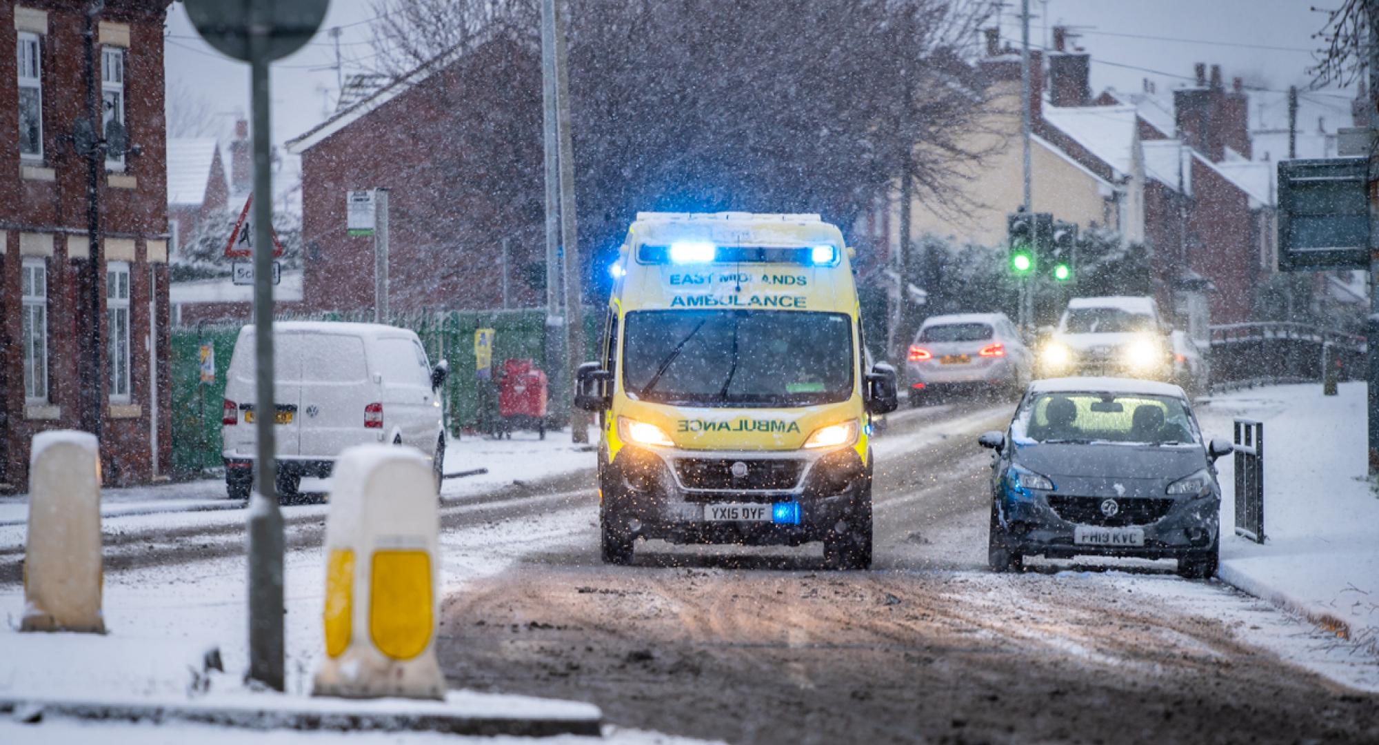 Ambulance driving through snow depicting the NHS winter pressures