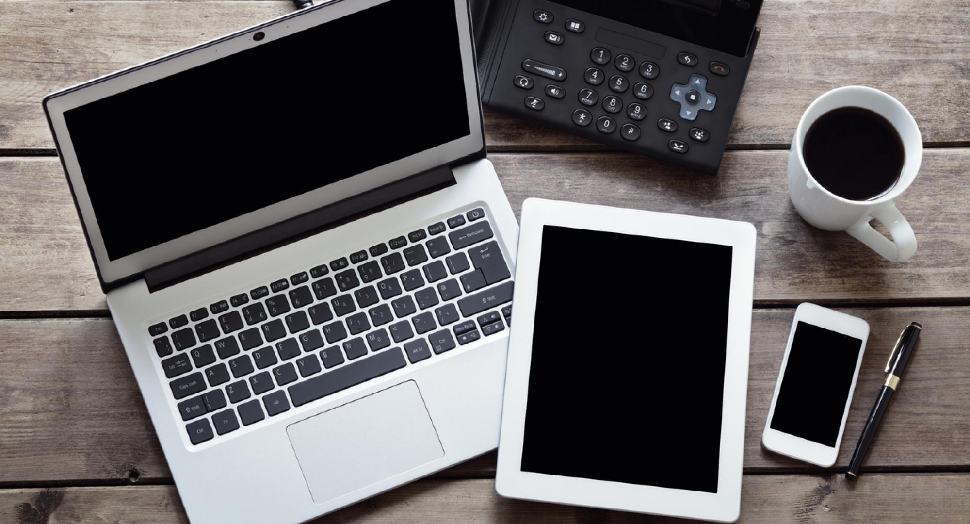 Overhead image of a laptop, tablet and phone depicting the NHS technology sector