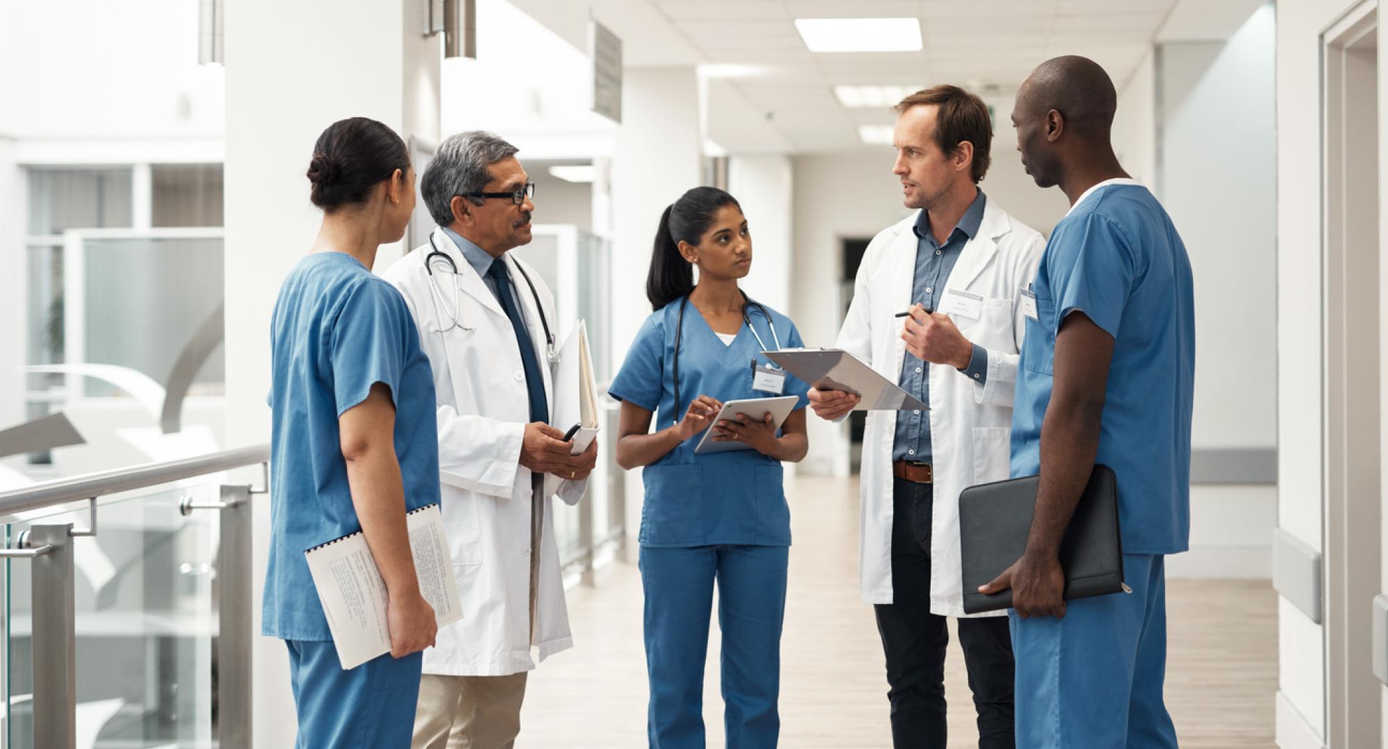 Group of healthcare professionals talking in a group depicting patient data sharing