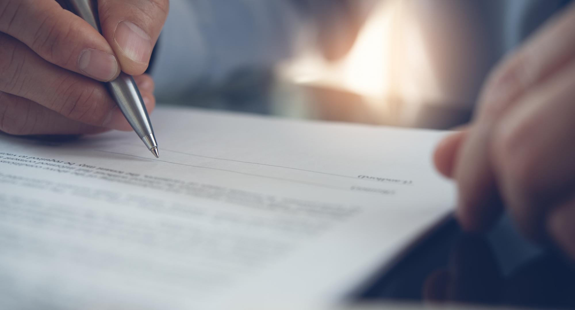 Image of a man signing a contract depicting the new deal for NHS consultants