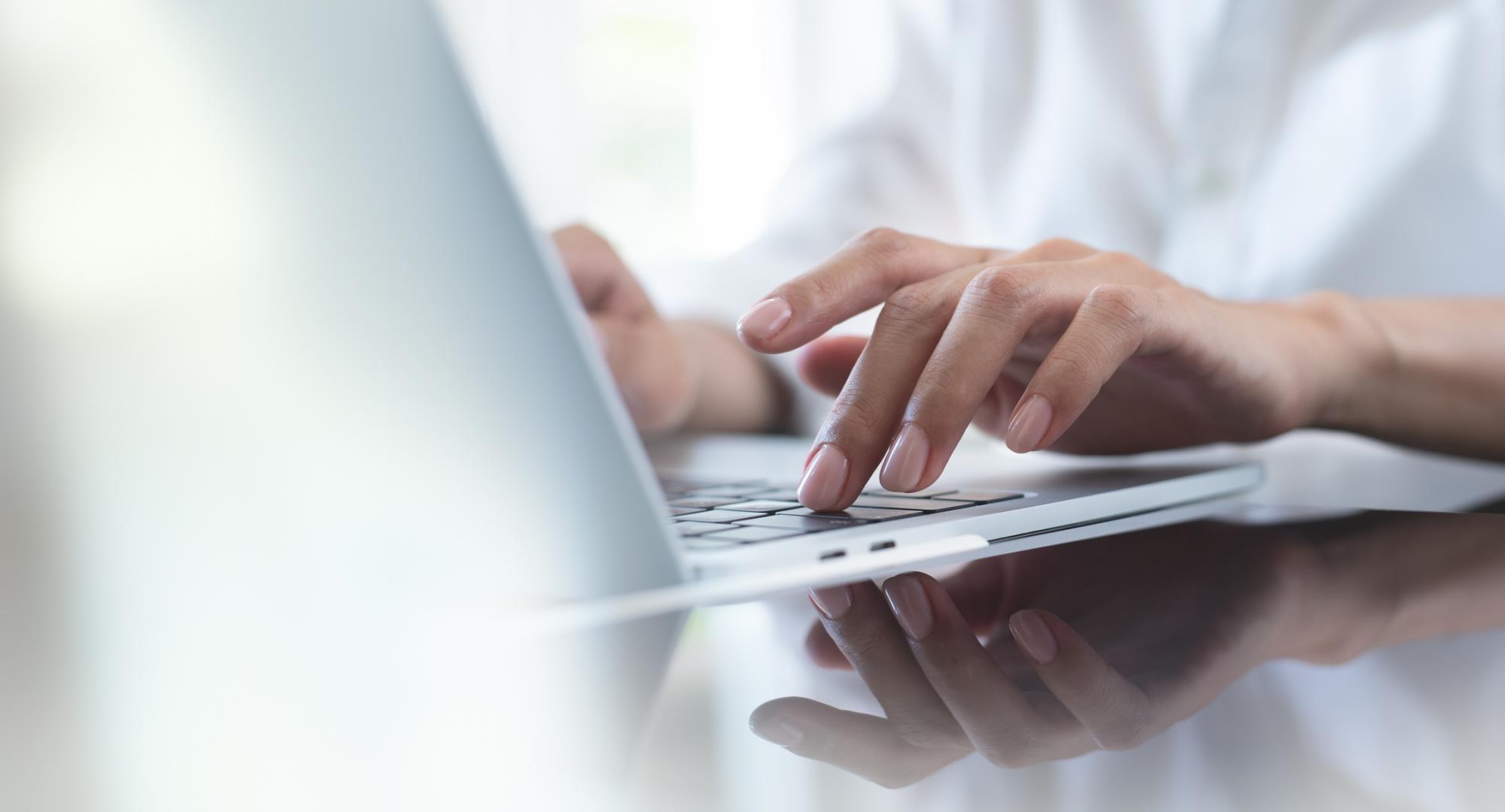 Woman's hand typing on a laptop keyboard