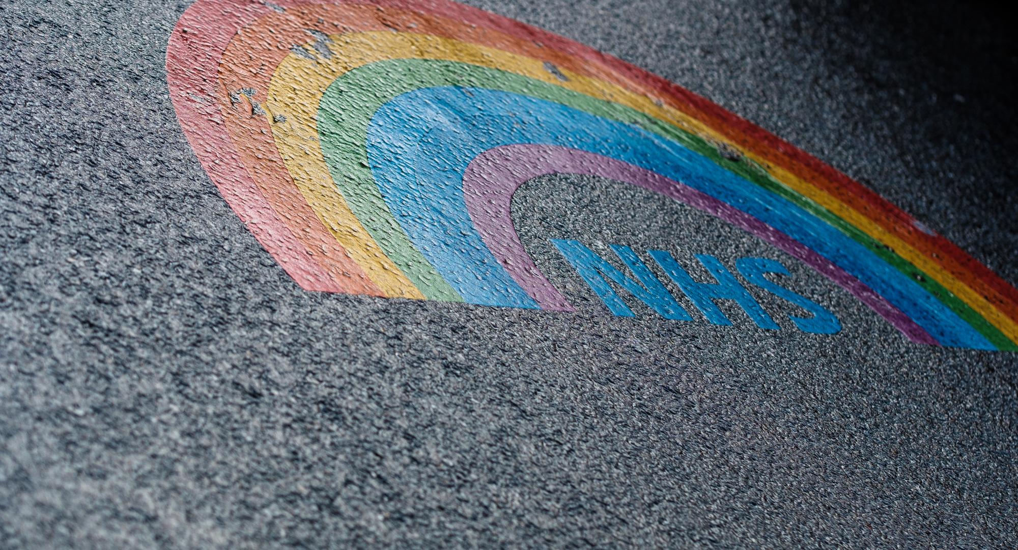 Lgbt rainbow NHS logo painted on asphalt.