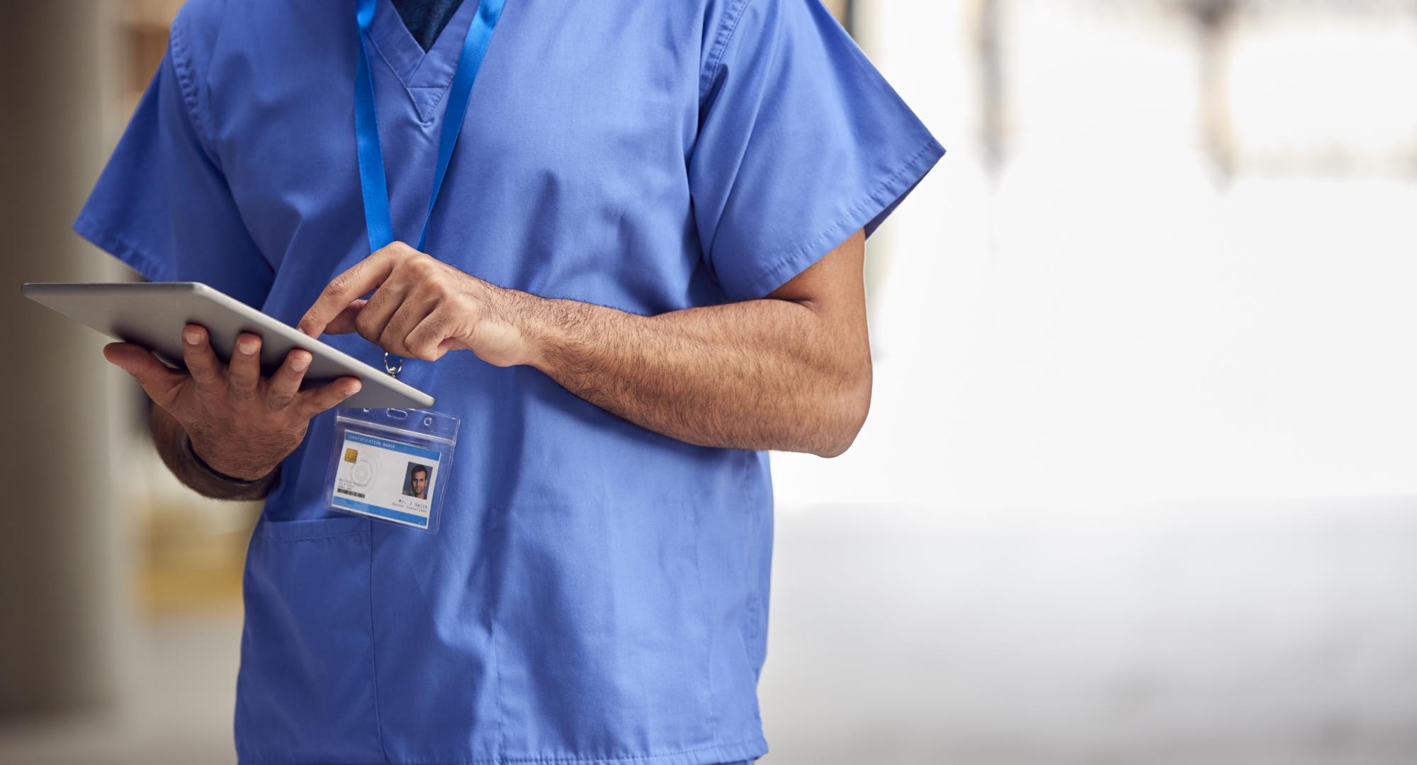 Male Medical Worker In Scrubs With Tablet