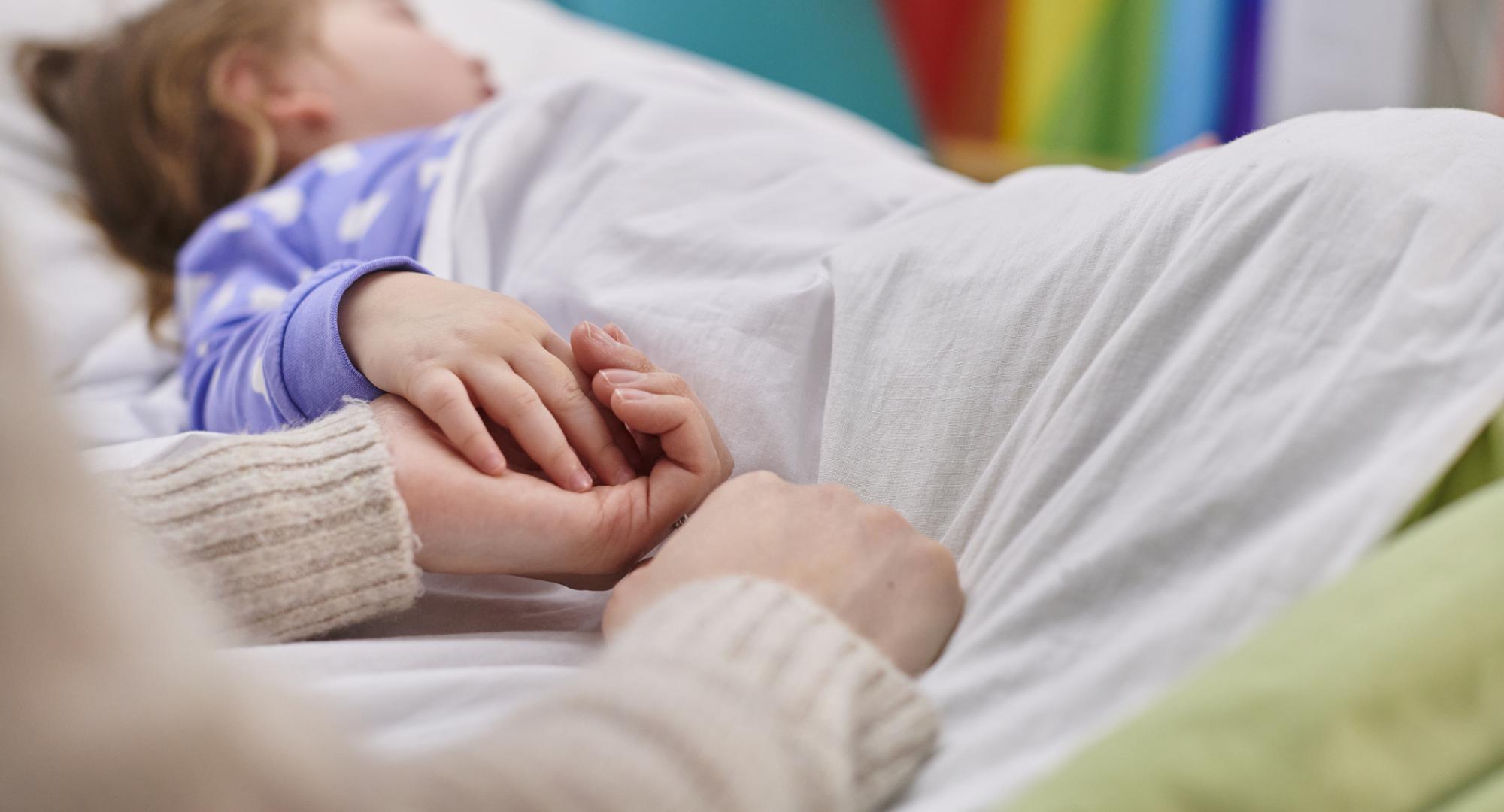 Mother and daughter holding hands in hospital