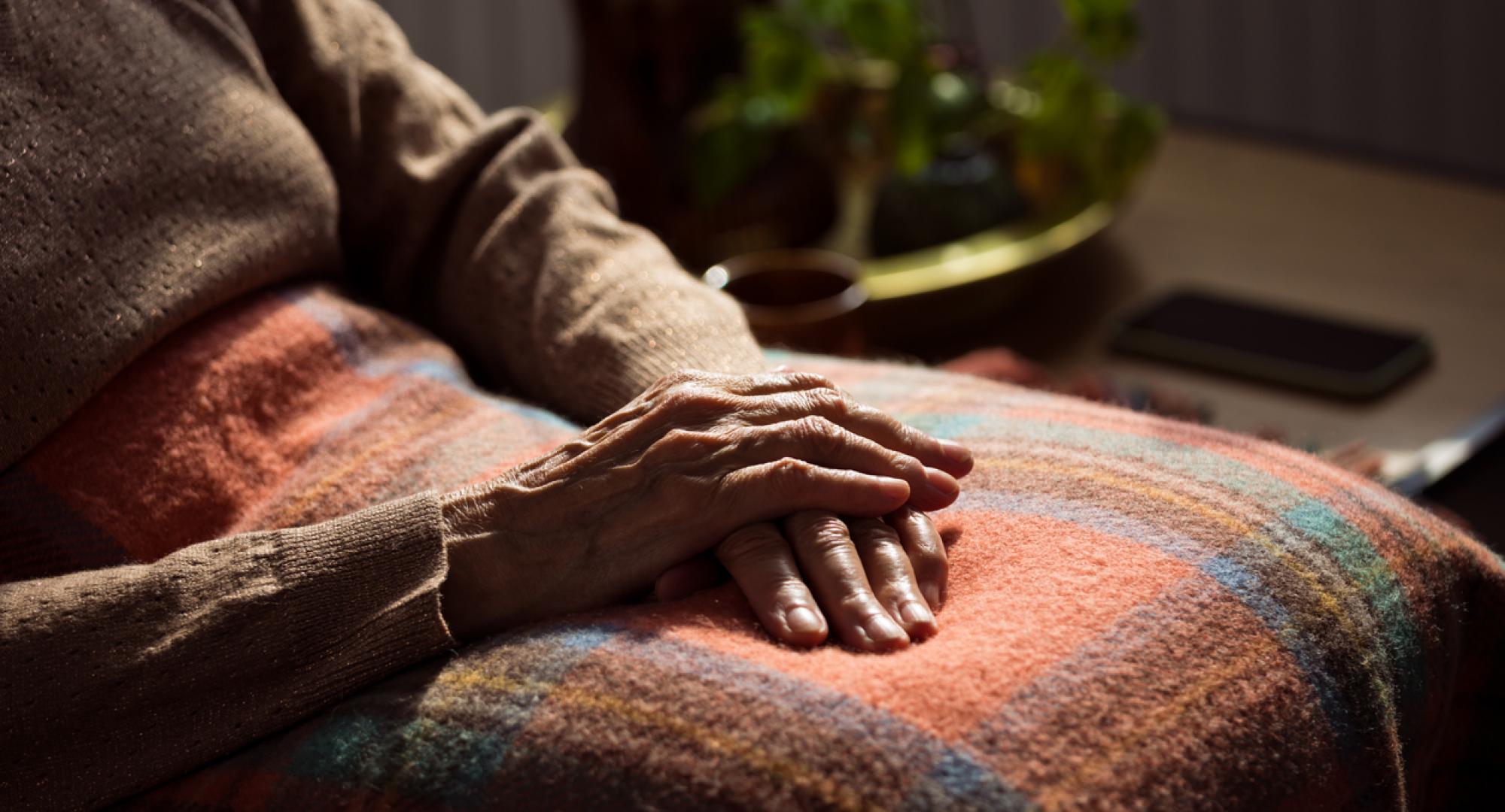 Senior woman sat under a blanket