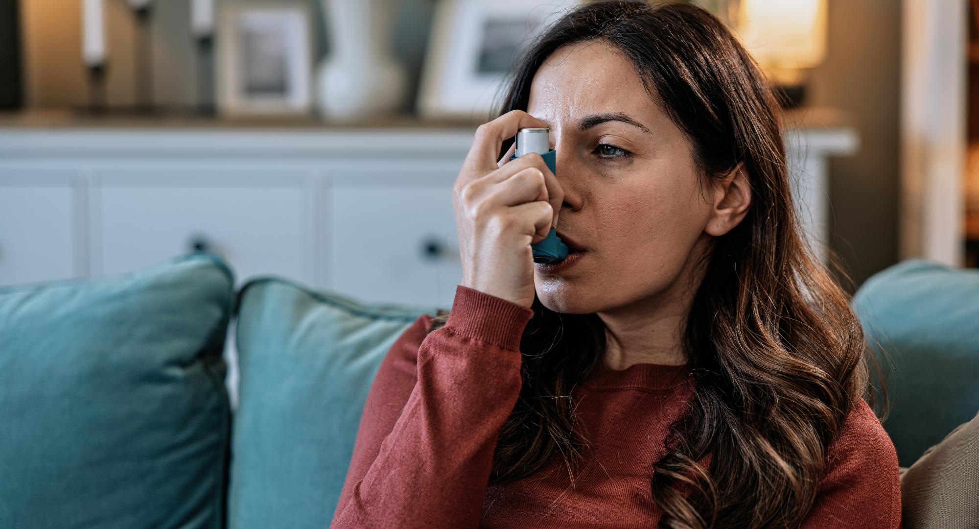 woman using her asthma inhaler at home