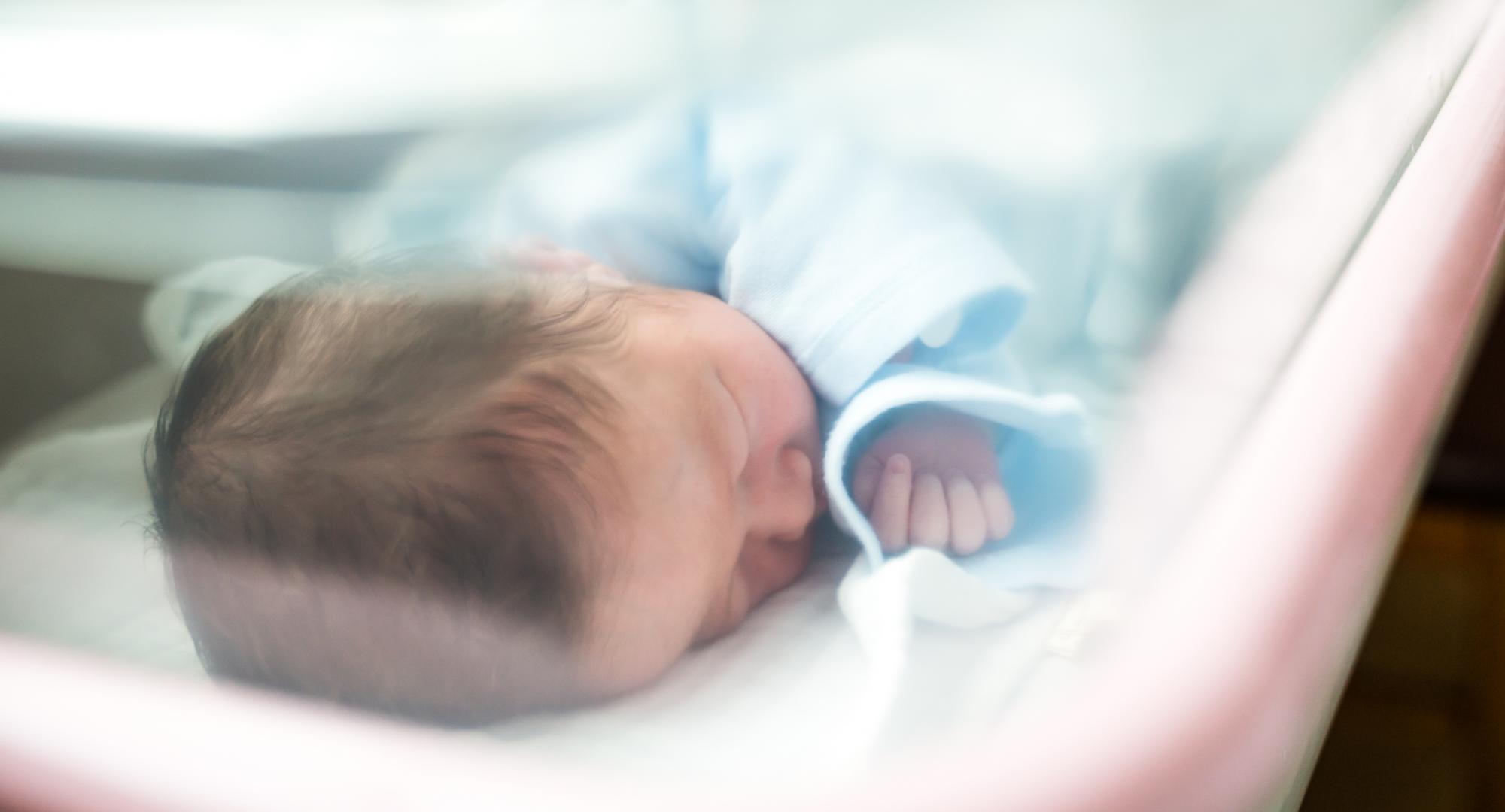 Newborn baby in hospital cot