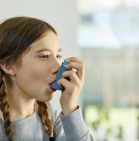 Young girl using asthma inhaler