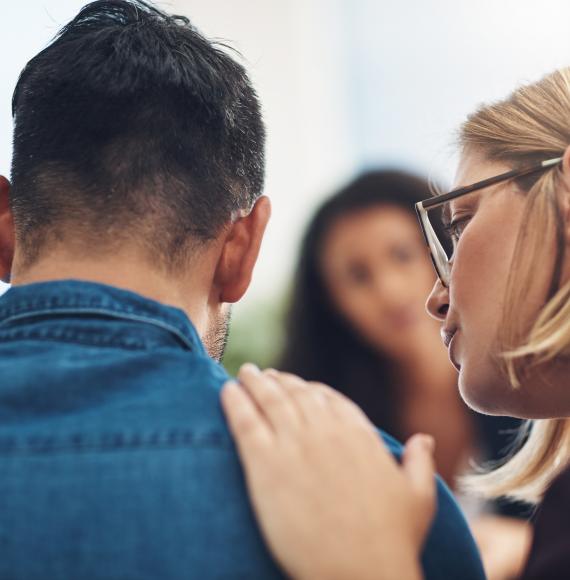 Behind, woman supporting hand on young man's shoulder