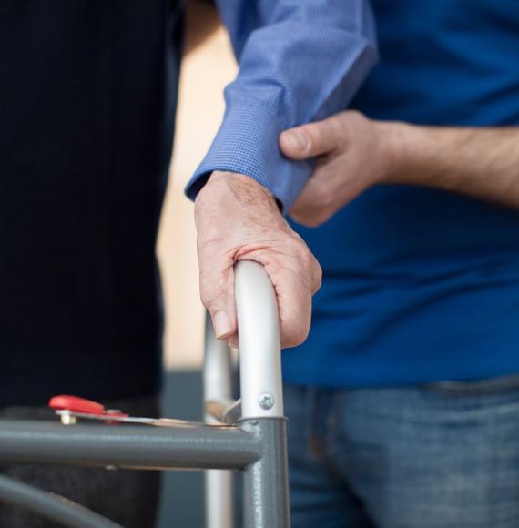 Hand supporting elderly man frame