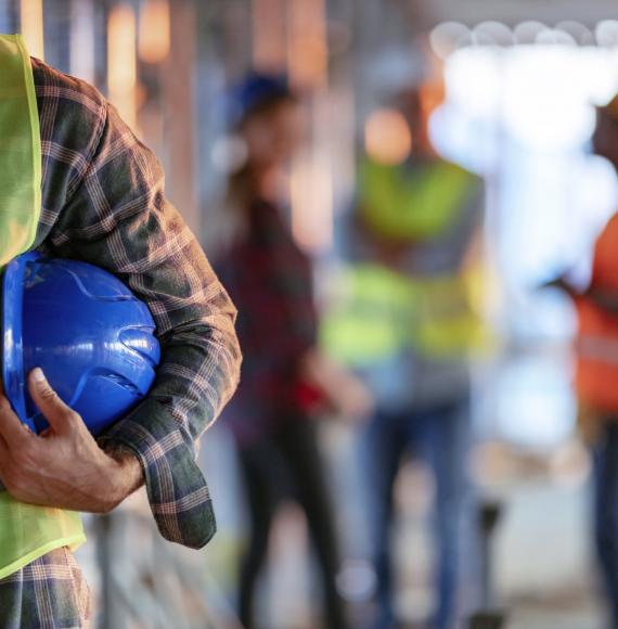 Workman holding hard hat tucked into elbow