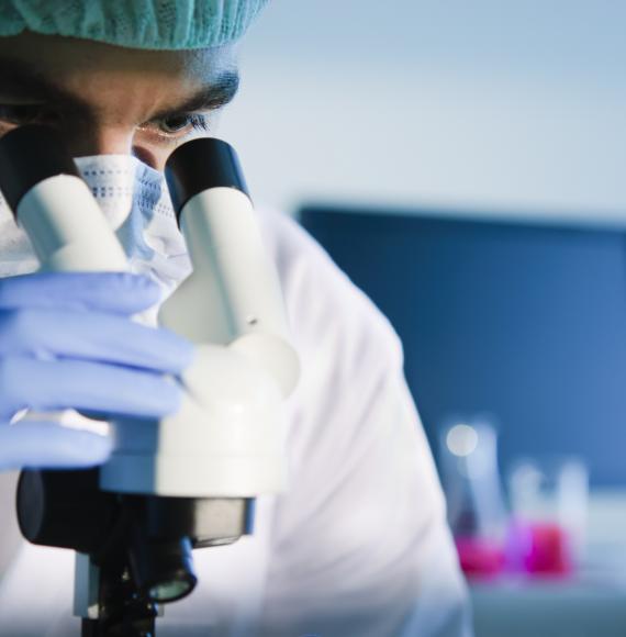 Male medical researcher using microscope