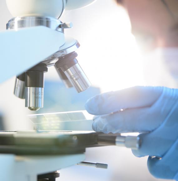 Health researcher using a microscope for research