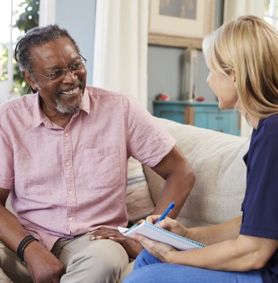 Female support worker talking with older male resident