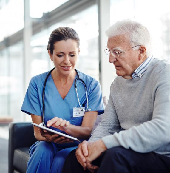 Female health professional with elderly patient using a tablet computer