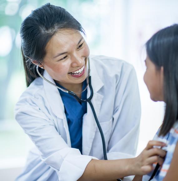 Female GP carrying out examination on young patient with stethoscope