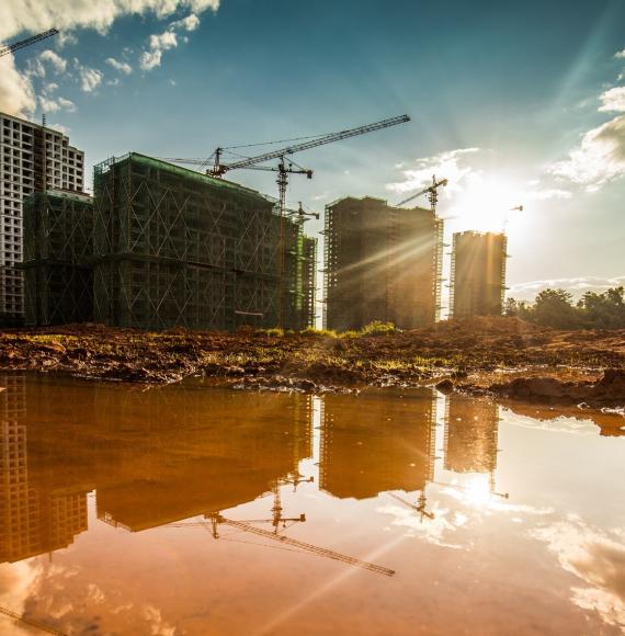 Construction site, with reflections off puddles on concrete in foreground